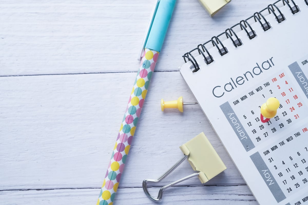 Calendar, Pins and Pen on a White Wooden Background